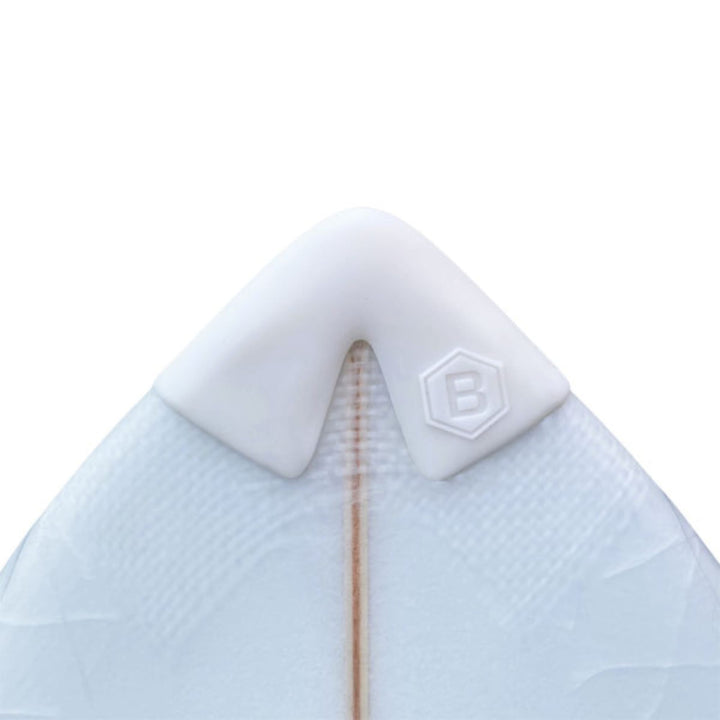 Nahaufnahme eines Buster-Surfboards-Surfbretts mit weißem Buster Surfboards Noseguard und sechseckigem "B"-Emblem an der Spitze; der Holzstringer des Bretts ist in der Mitte sichtbar.