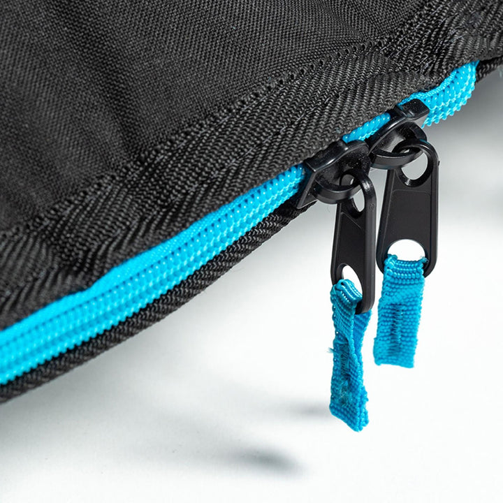 Nahaufnahme von zwei schwarzen Reißverschlüssen mit blauen Stofflaschen an einer schwarzen ROAM Boardbag Surfboard Daylight Hybrid Fish von Roam, mit einem hellblauen Reißverschluss. Der Fokus liegt auf dem Reißverschlussbereich und hebt die Textur und die Nahtdetails hervor.
