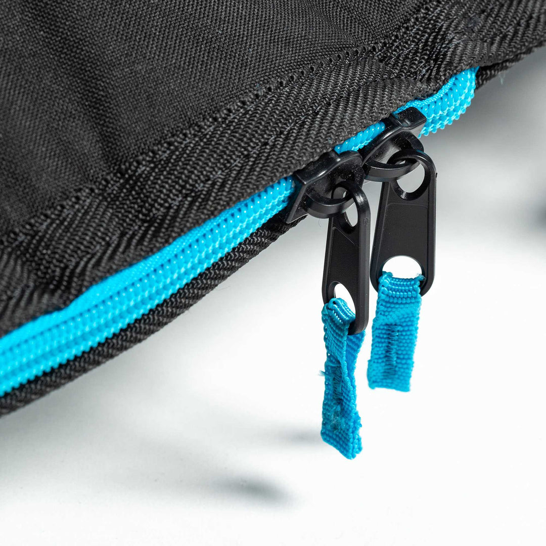 Nahaufnahme von zwei schwarzen Reißverschlüssen mit blauen Stofflaschen an einer schwarzen Roam ROAM Boardbag Surfboard Daylight Shortboard, die eine leuchtend blaue Reißverschlussleiste aufweist.