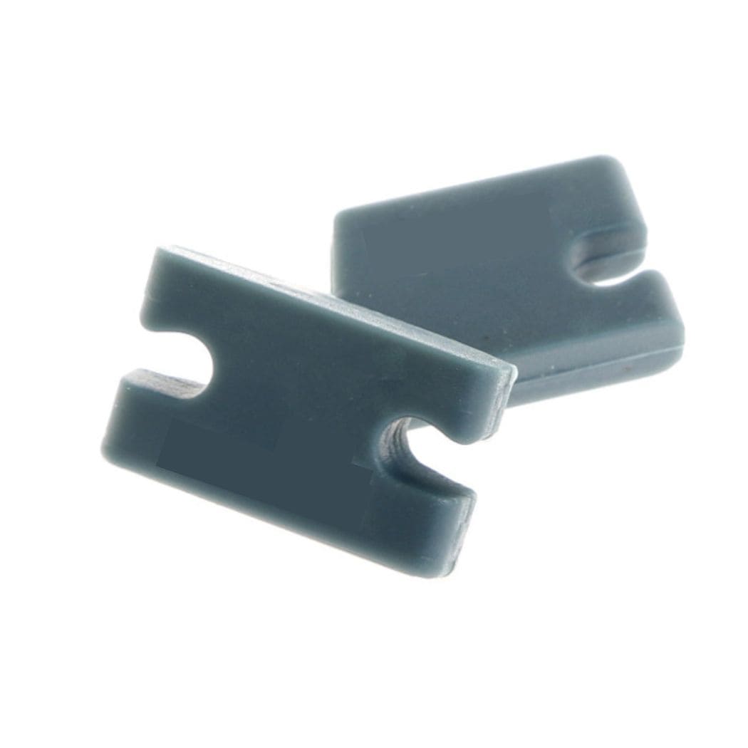 Zwei rechteckige dunkelgraue Kunststoffclips aus dem Rapid Surf Shop Tab Infill Kit, kompatibel mit FCS II Finboxen und mit gekerbten Öffnungen auf einer Seite. Auf weißem Hintergrund überlappt der eine Clip leicht den anderen.