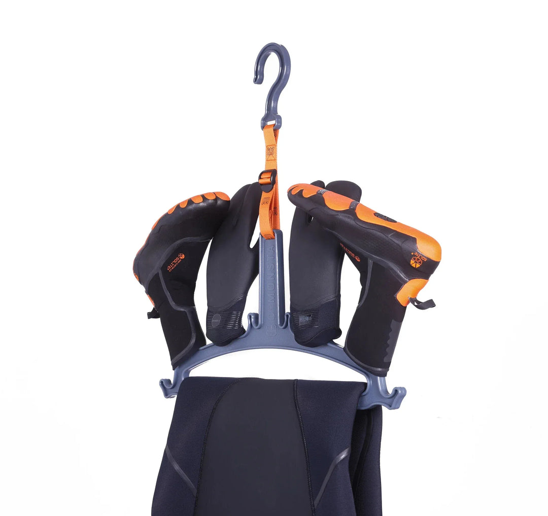 Der C-Monsta Wetsuit Aufhänger von C-Monsta hält schwarze und orangefarbene Wasserschuhe und einen gefalteten Neoprenanzug zum einfachen Trocknen, dargestellt auf einem schlichten weißen Hintergrund - das ideale Wassersport-Zubehör.
