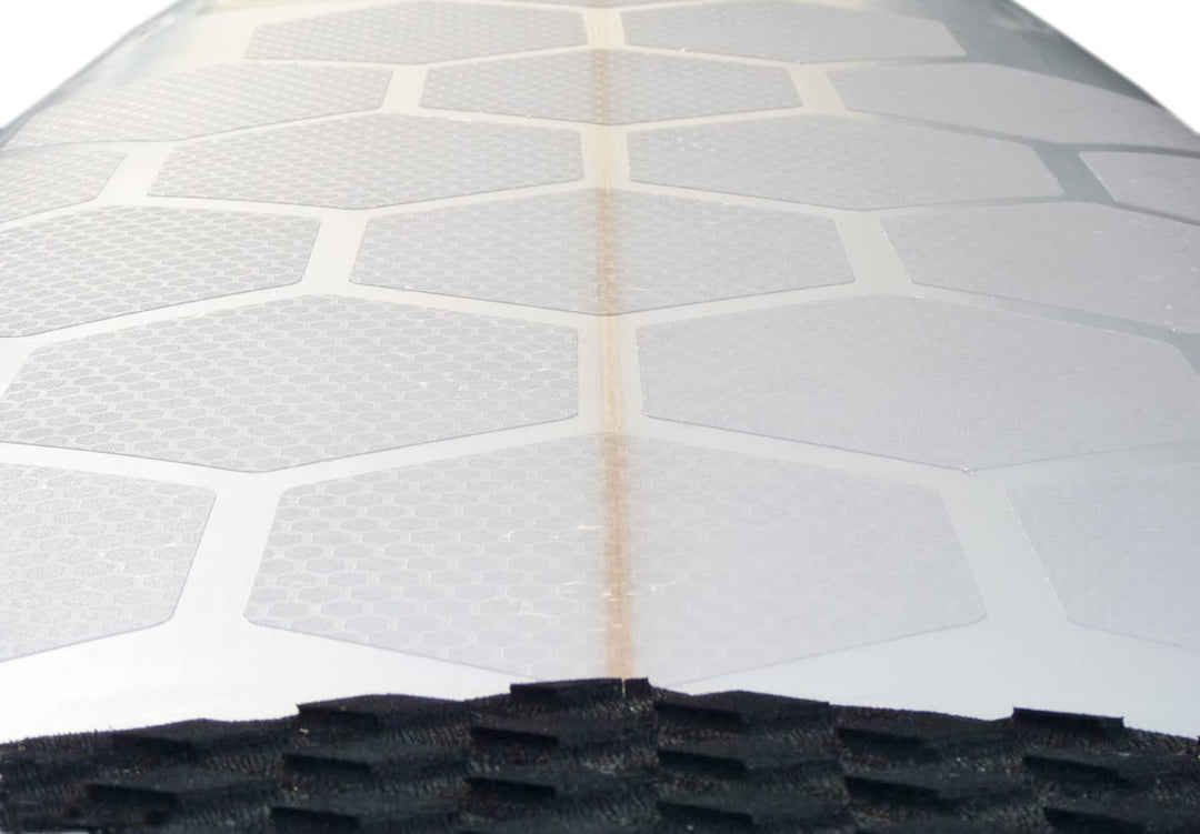 Nahaufnahme eines Surfboard-Decks mit reihenweise angeordneten RSPro - HexaTraction Pads (20 Stück) in Weiß und einem strukturierten schwarzen Grip Pad am unteren Ende.