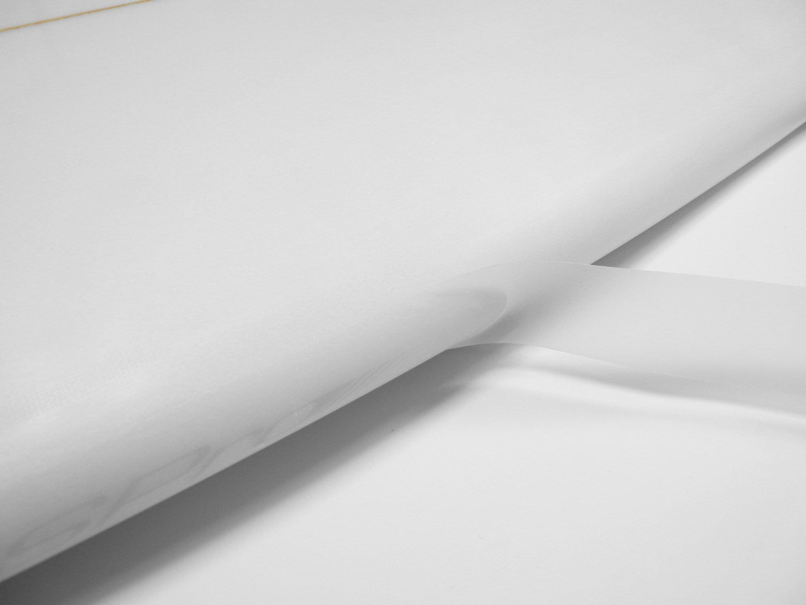 Eine Nahaufnahme eines weißen Surfbretts mit einer durchsichtigen Finne auf weißer Oberfläche ist mit dem RSPro Railsaver-Tape für verbesserten Schutz ausgestattet und zeigt das Engagement der Marke RSPro für die Langlebigkeit von Railschutz Surfboards.